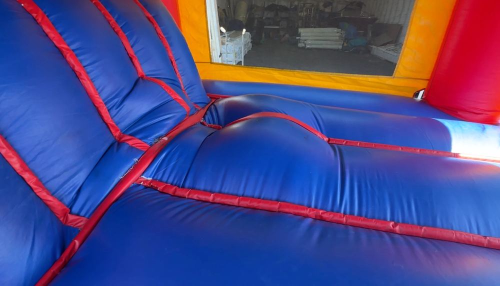 Before photo of frayed seam stitching repaired on a combo bounce house unit, completed by Stitches For Bounces