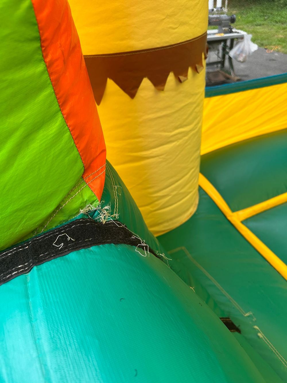 Before photo of a frayed seam torn open at a velcro panel on a combo bounce house, completed by Stitches For Bounces