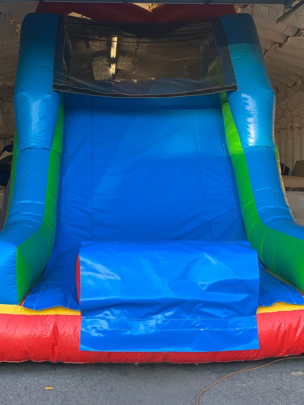 Real example of a custom water slide cover installed on an assembled unit with a mesh window, made by Stitches For Bounces