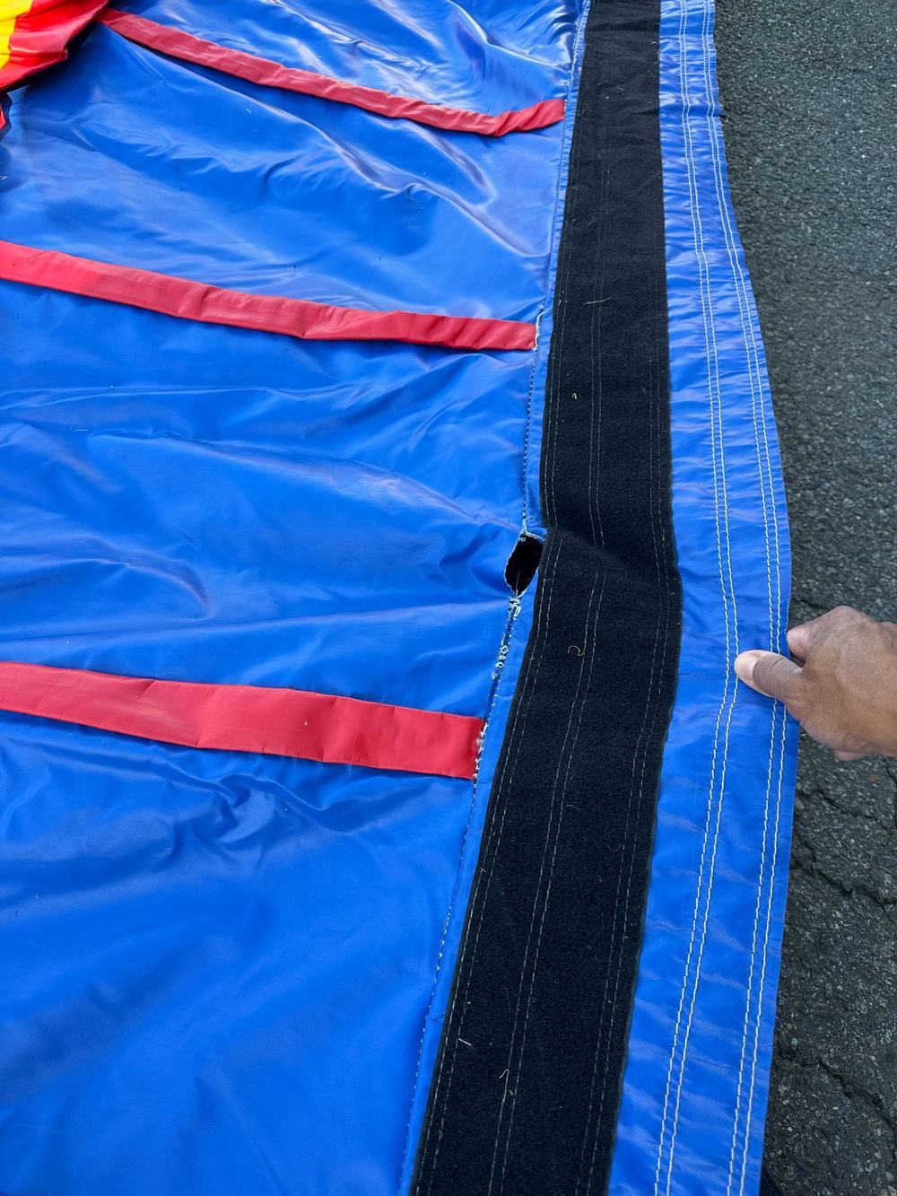 Before photo of a torn seam near the entrance of an obstacle course, completed by Stitches For Bounces