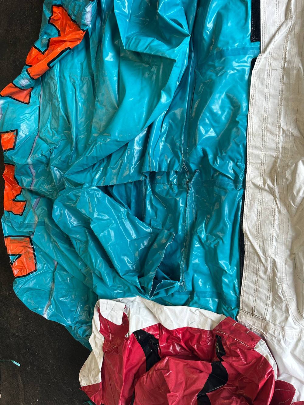 Before photo of a torn seam on a disassembled teal water slide panel, completed by Stitches For Bounces